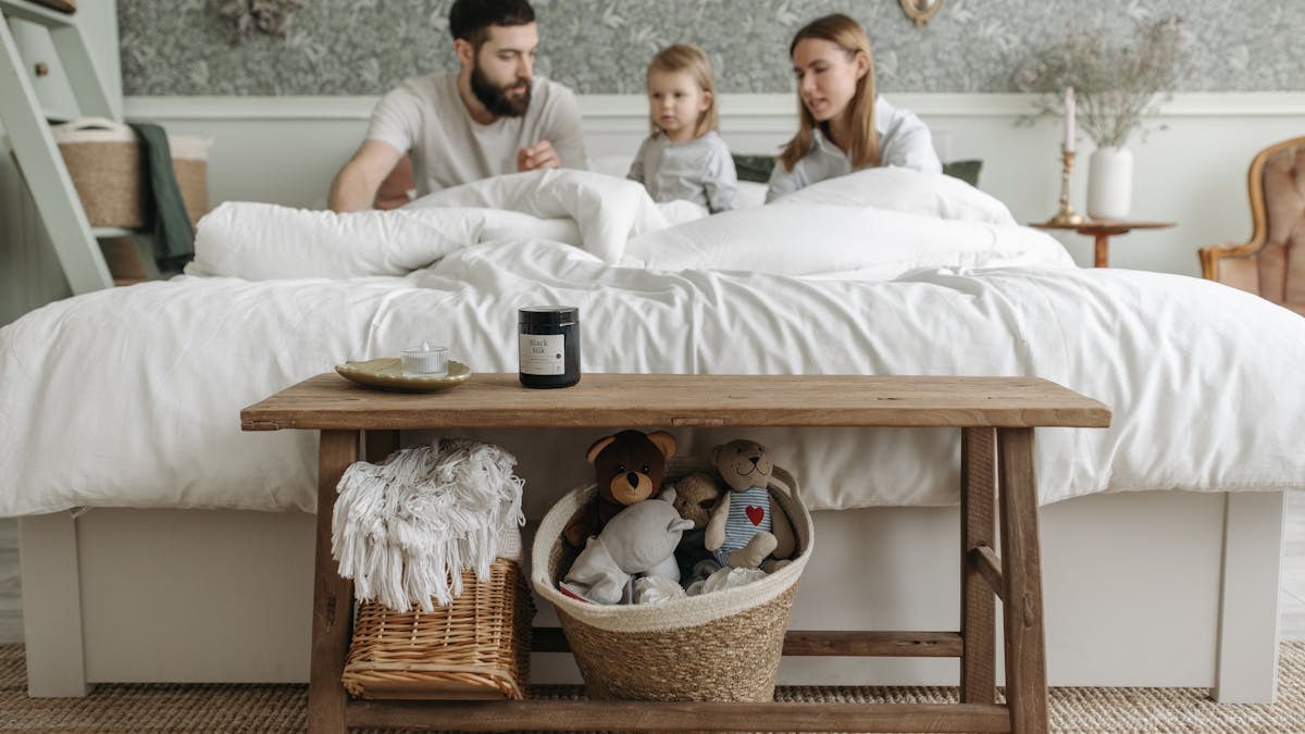 A family with a child enjoys a calm morning in a cozy and stylish bedroom setting.